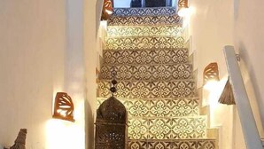 A staircase with ornate, patterned tiles leading to a balcony with a view of a mosque. - Riad Art House (El Jadida)