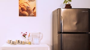 A kitchen with a stainless steel refrigerator, a table with a white tablecloth, and a vase with flowers. - D'Villa Guest House (Jaffna)