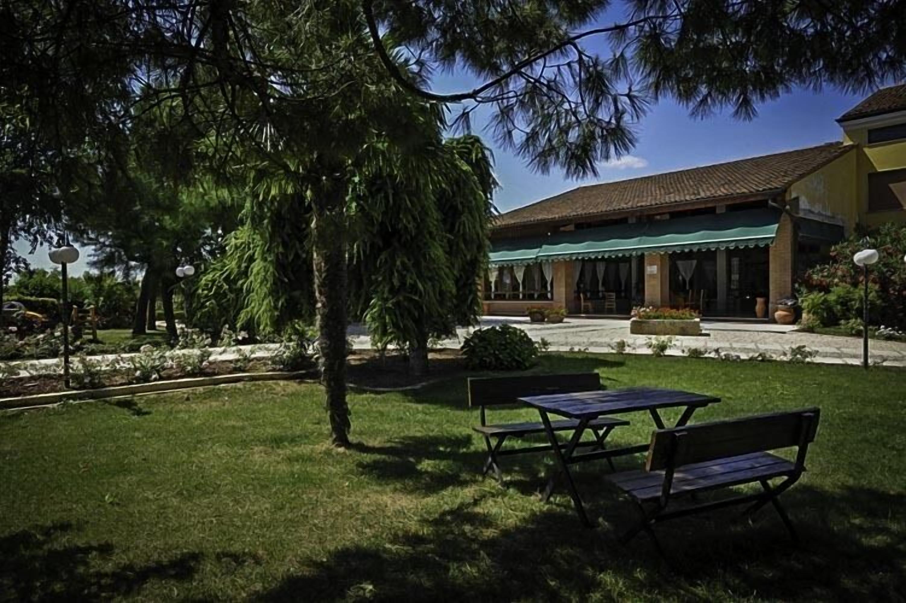 A building with a green awning, outdoor seating, and a well-maintained garden.