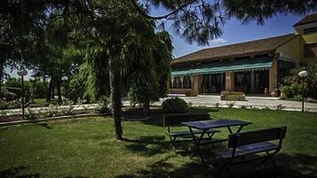 A building with a green awning, outdoor seating, and a well-maintained garden.