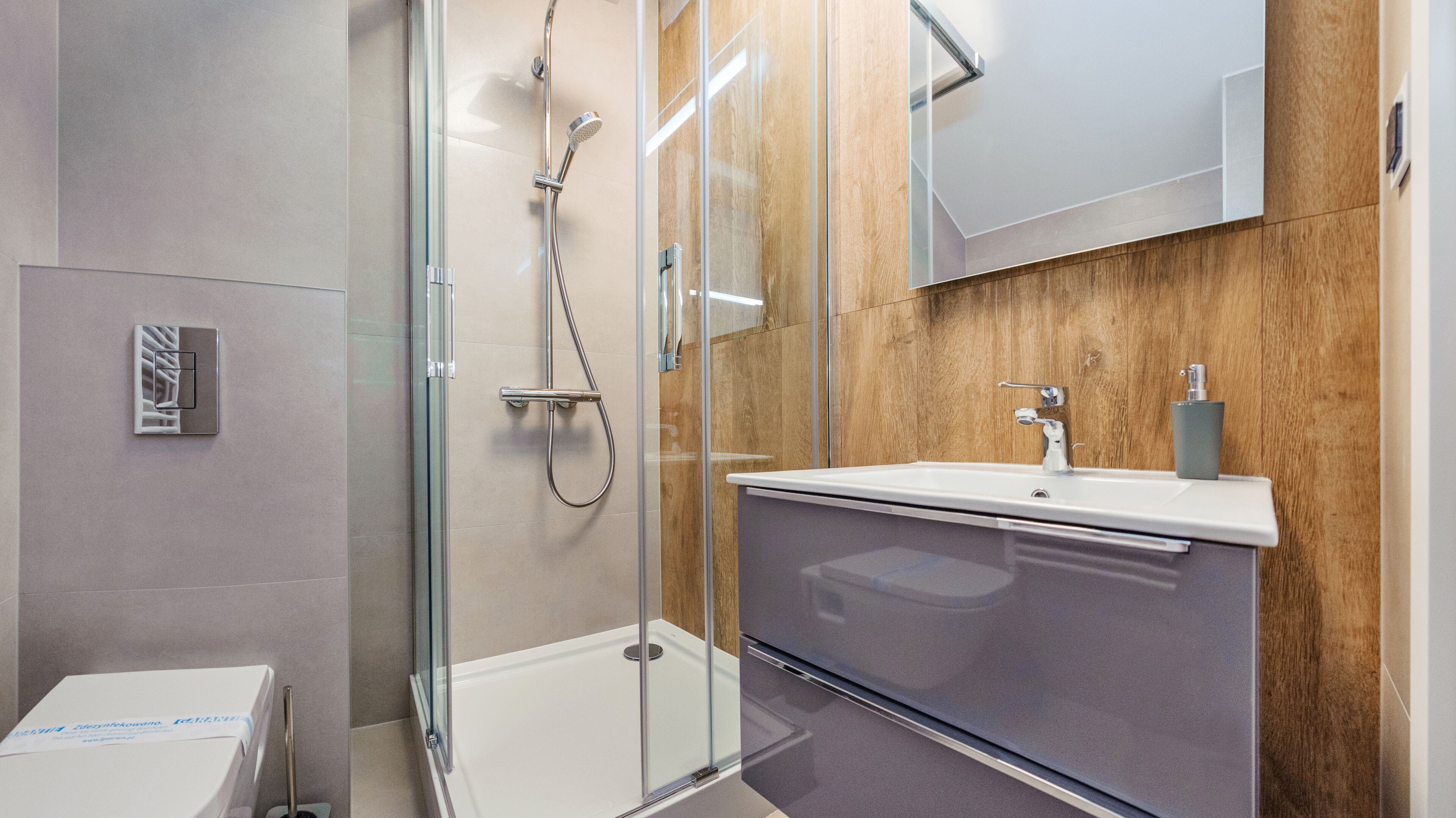 A modern bathroom with a glass-enclosed shower, a vanity with a sink, and a wooden accent wall.