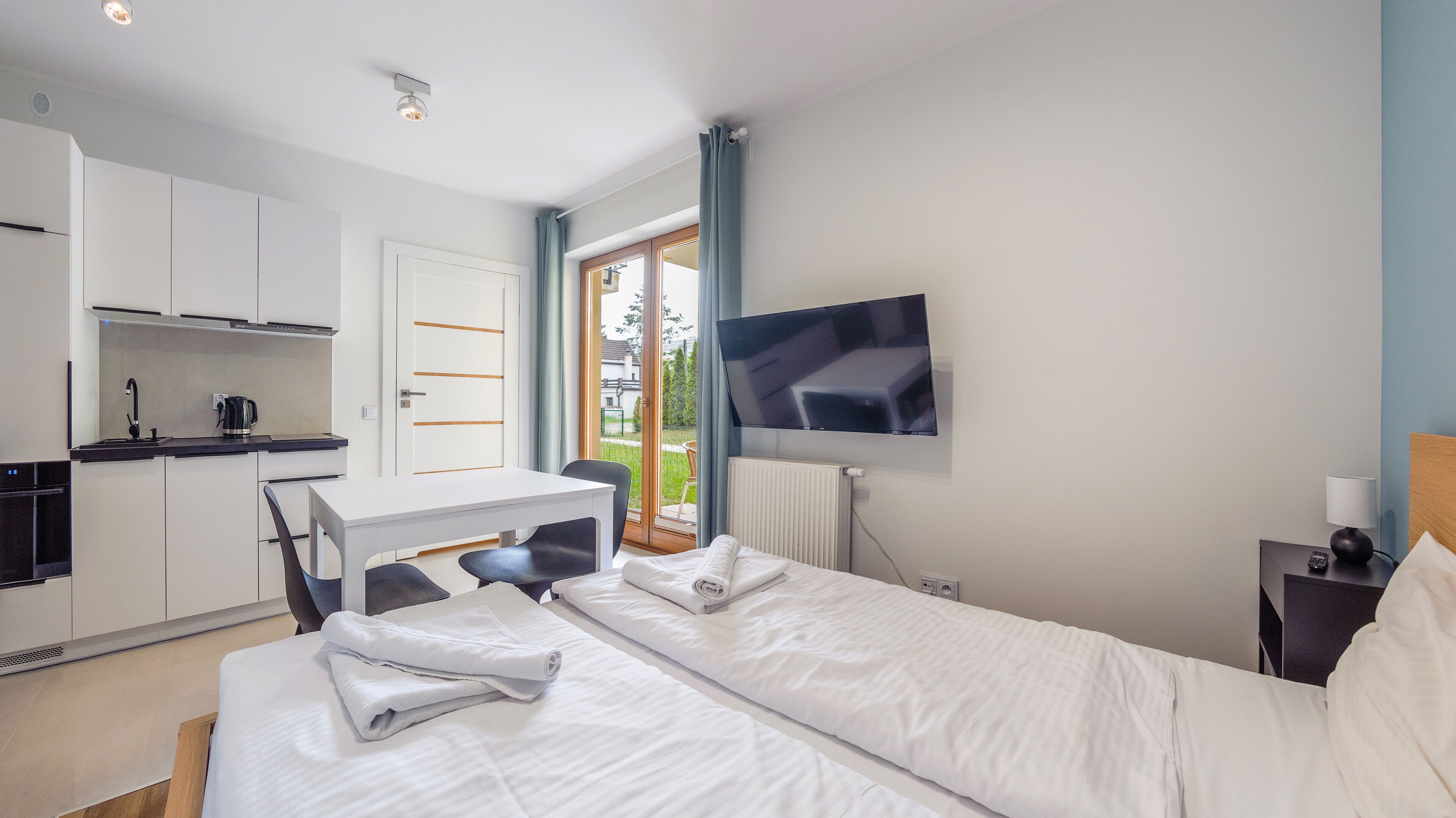 Ein Hotelzimmer mit Bett, Schreibtisch, Stuhl, Fernseher und Küchenzeile.