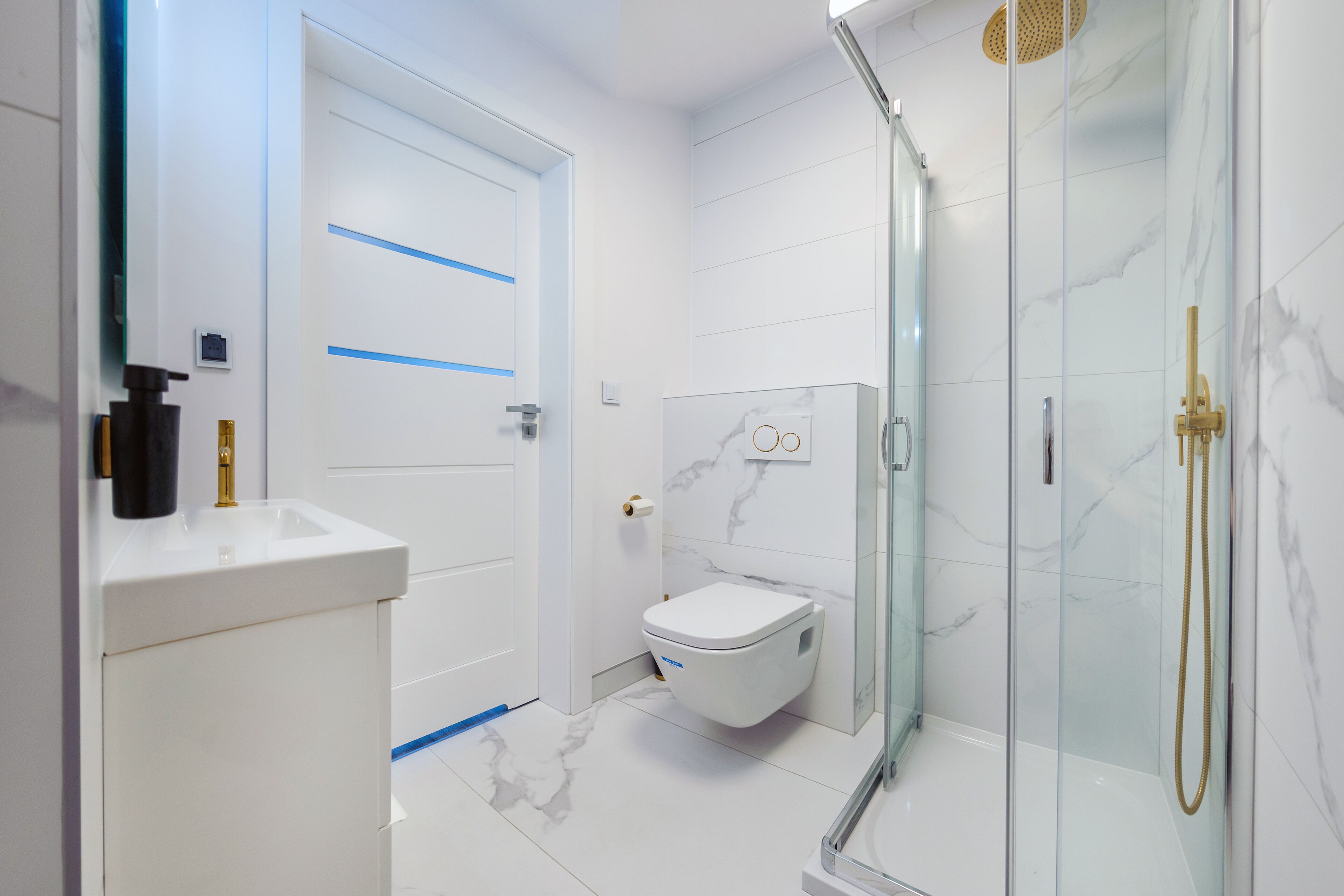 A modern bathroom with a toilet, sink, and glass-enclosed shower.