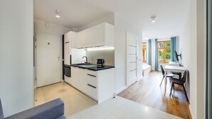 A modern kitchen with white cabinets, a black countertop, and a kettle.