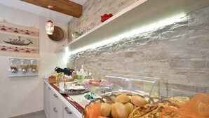 A buffet area with various food items, including bread and pastries, and a stone wall backdrop. - B&BIssicoro Baunei (Baunei)