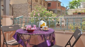A balcony with a table set for tea, a chair, and a flower arrangement. - B&BIssicoro Baunei (Baunei)