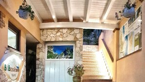 A stone facade with a door, a potted plant, and a sign for B&B Biscicoro. - B&BIssicoro Baunei (Baunei)