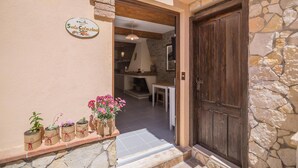 A stone wall entrance with a wooden door, a sign reading "SalaColazione", and potted plants on the steps. - B&BIssicoro Baunei (Baunei)