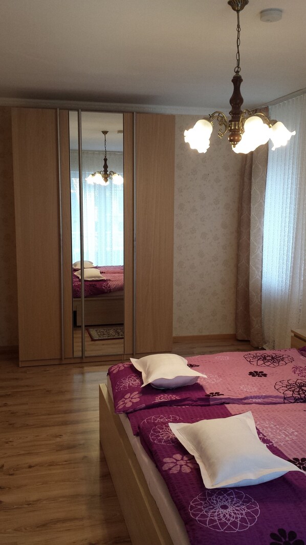 A bedroom with a bed, a wardrobe, and a chandelier.