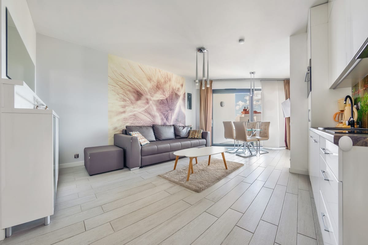 Una sala de estar moderna con un sofá gris, una mesa de centro blanca y un cuadro abstracto grande en la pared.