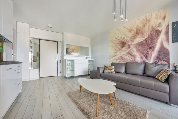 A modern living room with a grey sofa, a white coffee table, and a large abstract painting on the wall. - Sun & Snow, Horyzont Międzyzdroje (Miedzyzdroje)