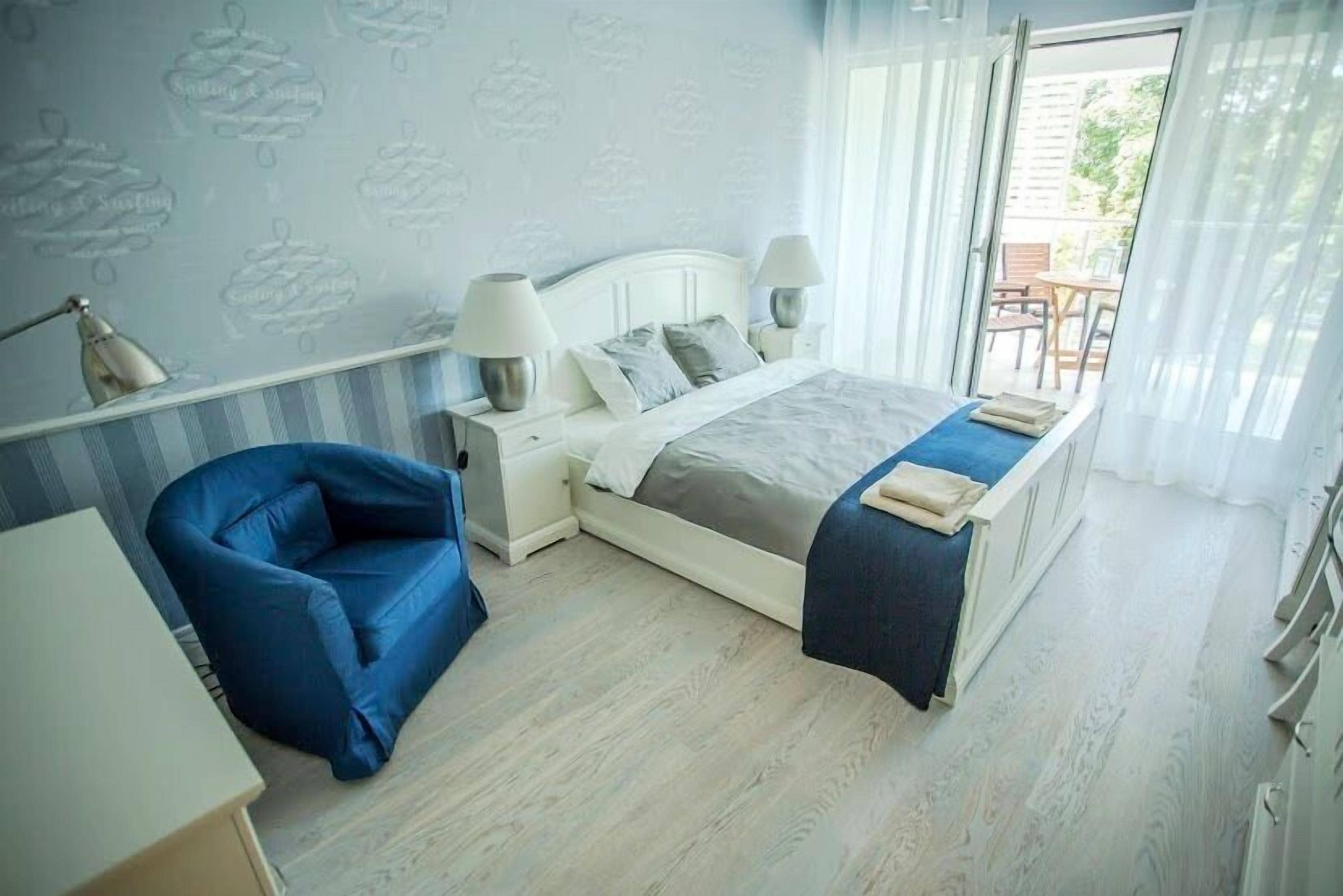 Un dormitorio con cama, lámparas de noche, una silla y un escritorio.