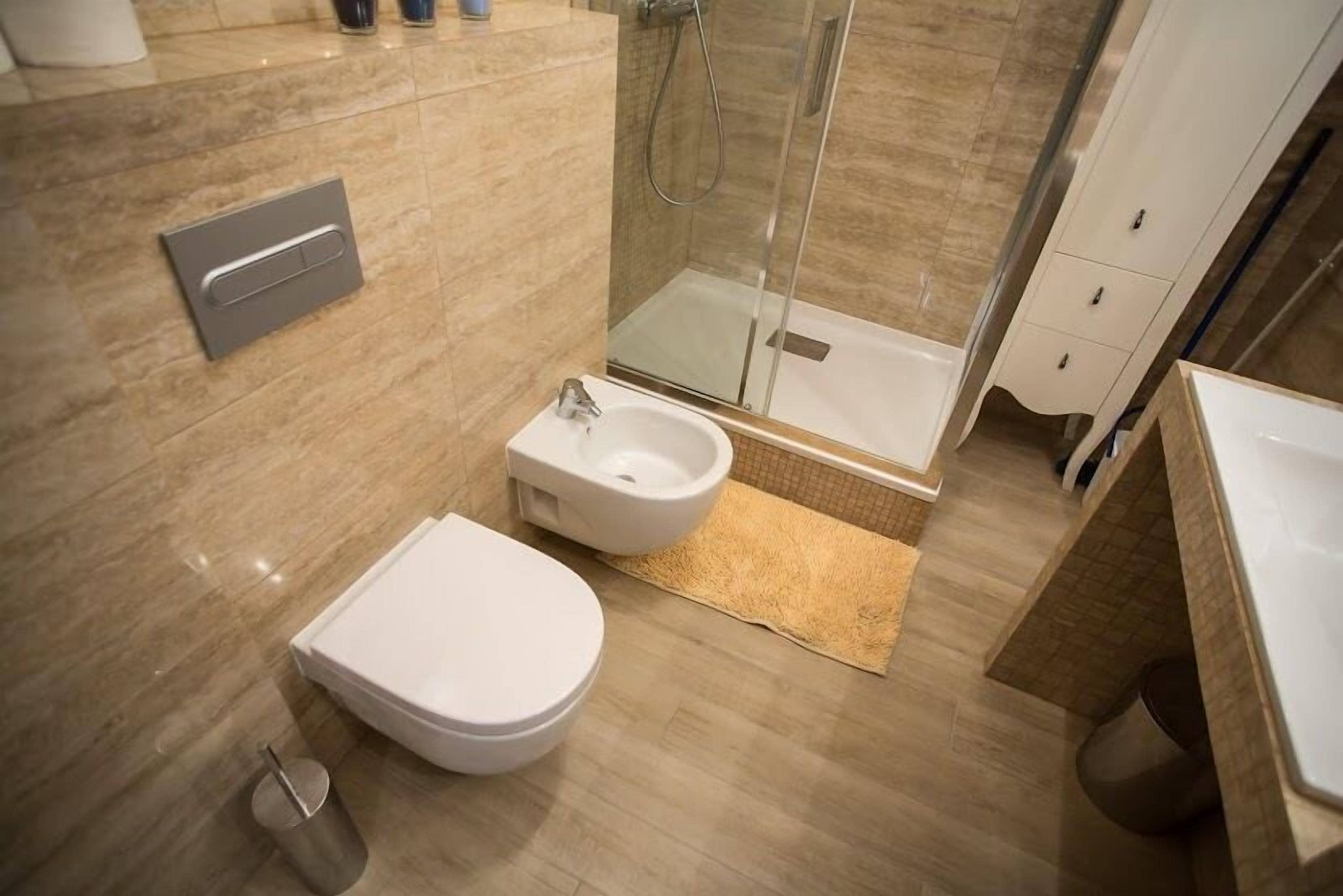 Une salle de bain moderne équipée de toilettes, d’un bidet et d’une douche à parois de verre.