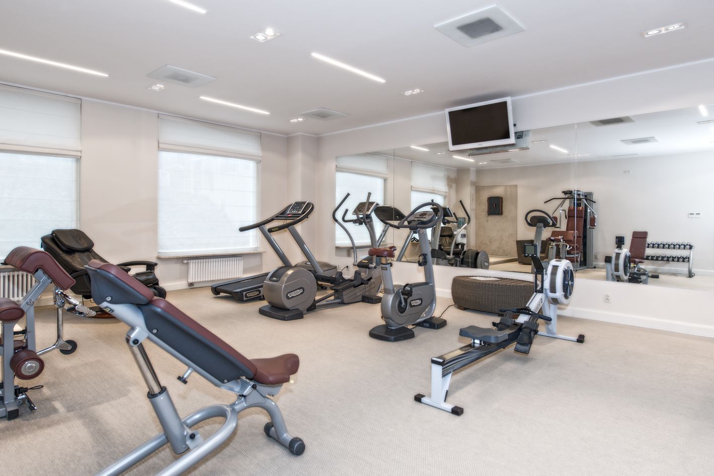 Un gimnasio con diverso equipo de ejercicio, incluyendo cintas de correr, bicicletas estáticas y máquinas de pesas.