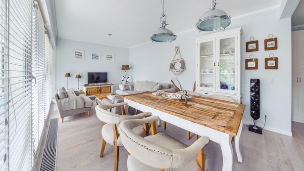 A modern living room with a wooden dining table, beige sofas, and a TV. - Apartamenty Sun & Snow Playa Baltis (Miedzyzdroje)