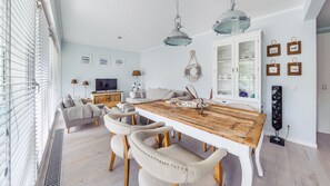 A modern living room with a wooden dining table, beige sofas, and a TV. - Apartamenty Sun & Snow Playa Baltis (Miedzyzdroje)