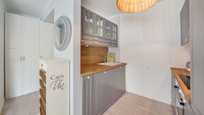 A modern kitchen with grey cabinets, a wooden countertop, and a hanging light fixture. - Apartamenty Sun & Snow Playa Baltis (Miedzyzdroje)