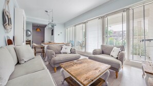 A modern living room with a sofa set, a wooden coffee table, and large windows with blinds. - Apartamenty Sun & Snow Playa Baltis (Miedzyzdroje)