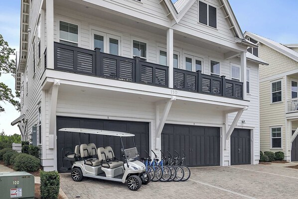 A two-story residential building with a garage, a covered patio, and a row of bicycles.