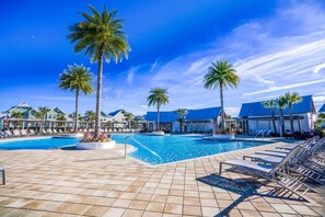 A resort pool area with multiple pools, palm trees, and lounge chairs.