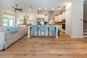 A modern kitchen with a central island, white cabinetry, and a ceiling fan.
