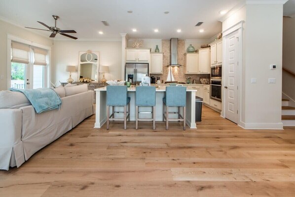 A modern kitchen with a central island, white cabinetry, and a ceiling fan.