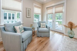 A room with a light blue sofa, a matching armchair, and a glass vase with dried plants.