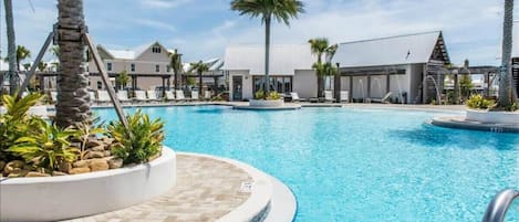 Una piscina con sillas de descanso y palmeras, rodeada de edificios con diseño moderno.