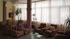 A living room with four brown armchairs, a glass coffee table, and a chandelier.
