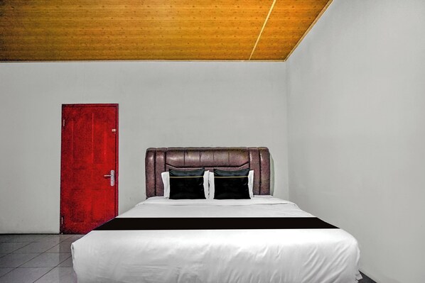 A bedroom with a bed, a red door, and a wooden ceiling.