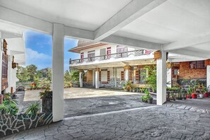 A covered outdoor area with a building, potted plants, and a stone pathway. - Collection O near Museum Pusaka Karo formerly 3 Berastagi (Medan)