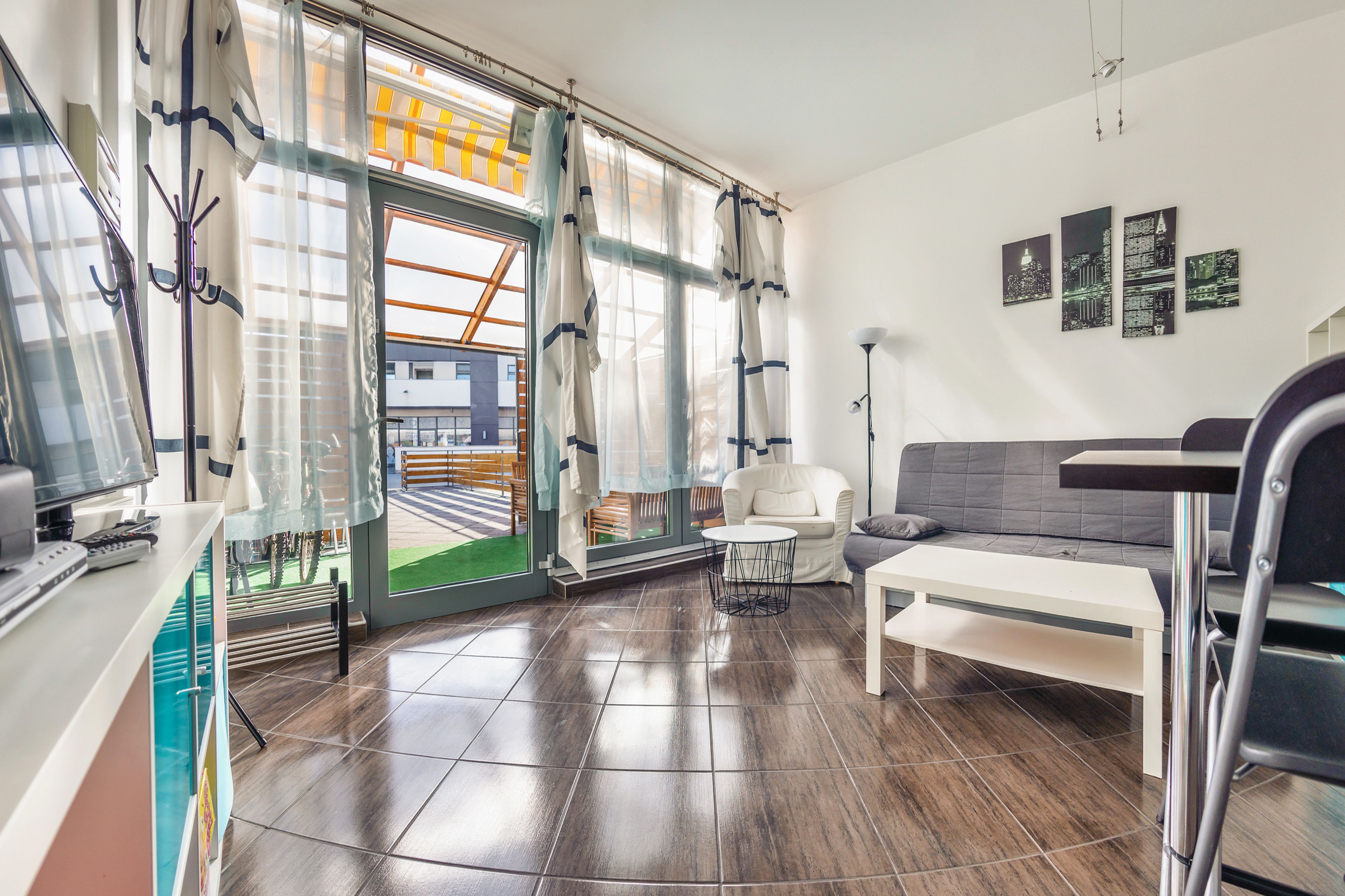 Una sala de estar moderna con un sofá, una mesa de centro y vistas al exterior a través de una puerta de cristal.