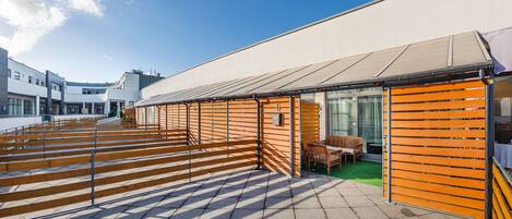Un edificio moderno con un área de estar al aire libre cubierta y un espacio verde.