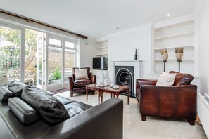 A living room with a fireplace, leather sofas, and a television. - Beautiful House in Heart of Kensington (London)