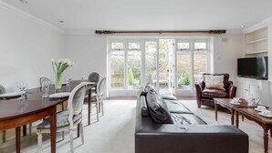 Un coin repas avec une table en bois dressée pour quatre personnes, un canapé et un téléviseur posé sur un meuble.