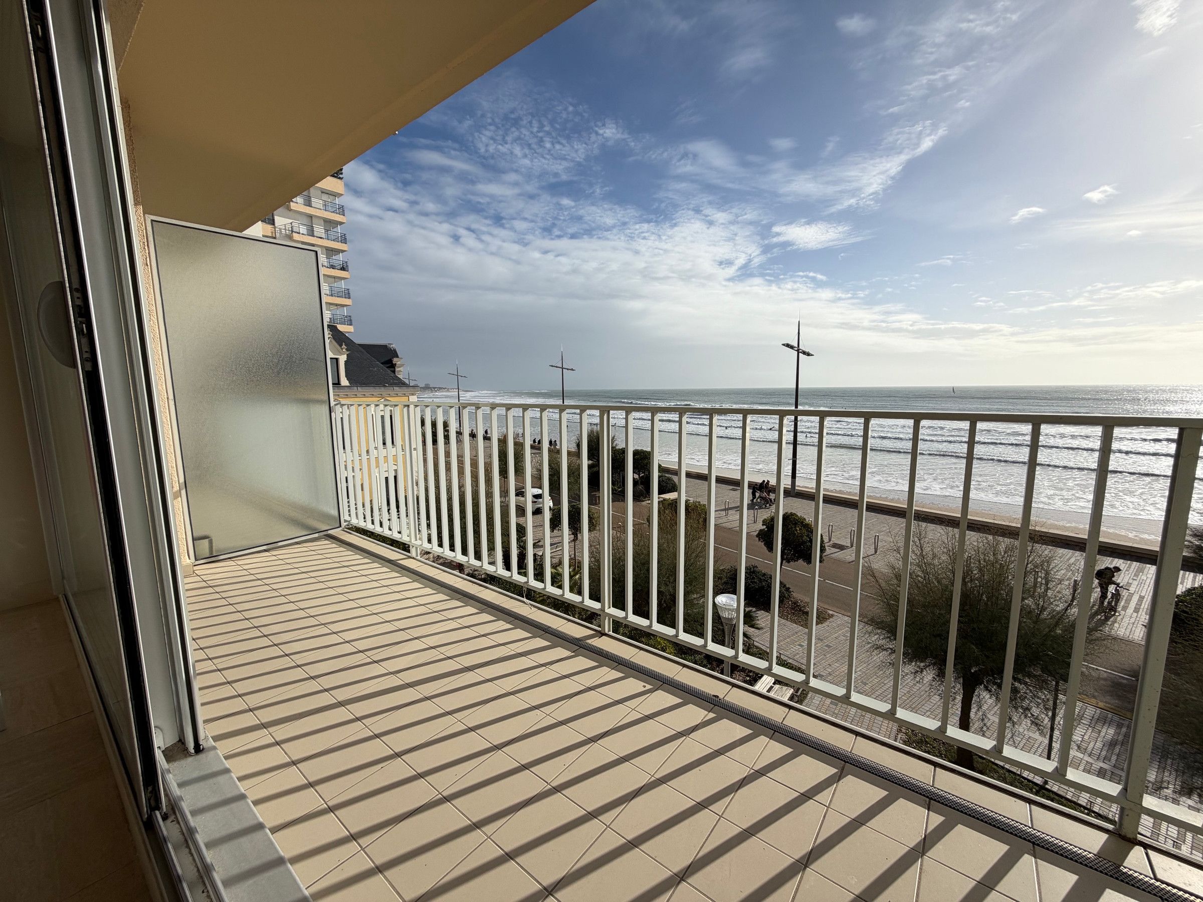 A balcony with a view of the sea and a pedestrian path.
