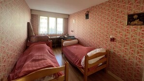Une chambre avec deux lits en bois, un bureau et une chaise.