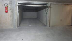 Un intérieur en béton avec un extincteur fixé au mur, une porte en métal et un portail en métal.