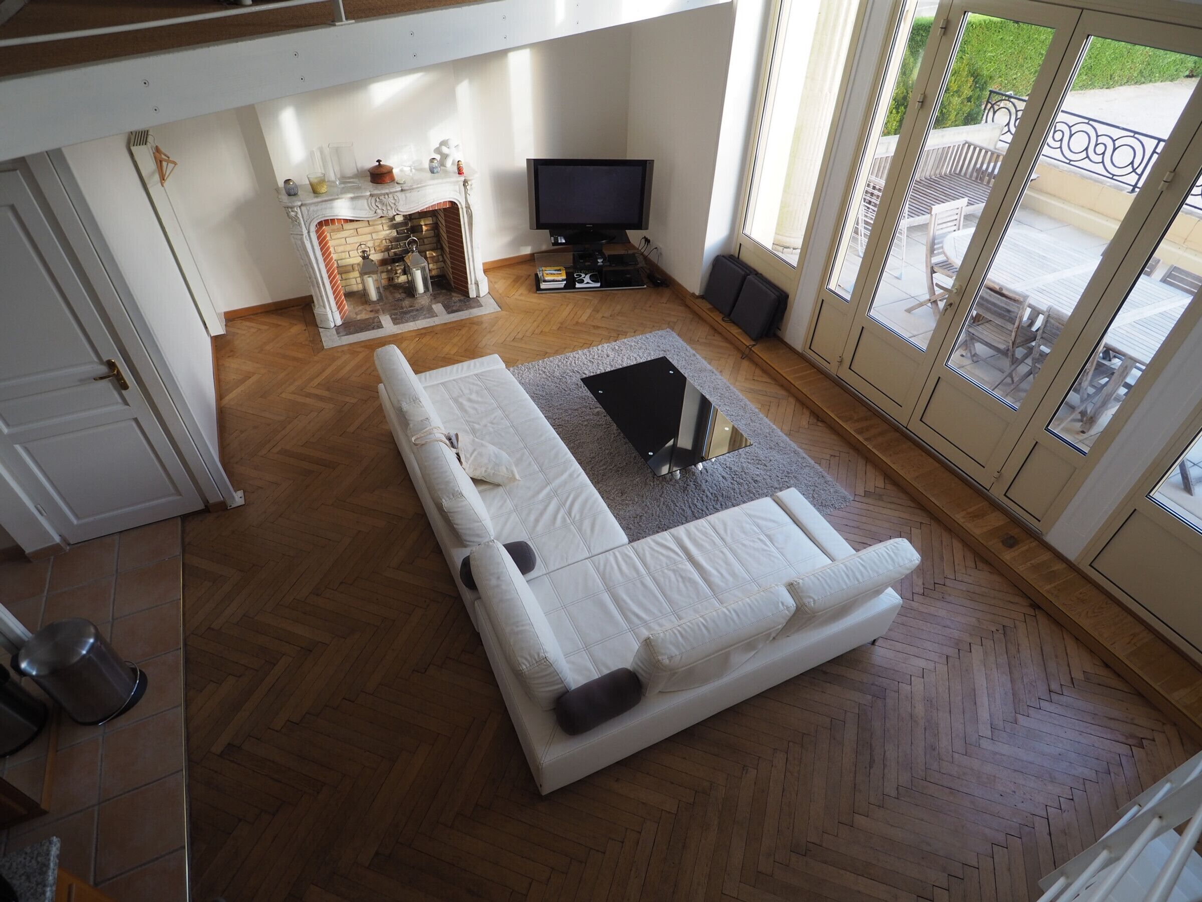 Un salon moderne avec un canapé blanc, une cheminée, un téléviseur et de grandes fenêtres.