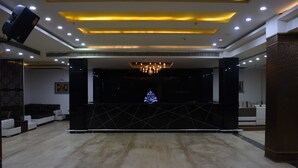 A reception area with a modern design, featuring a black reception desk, a chandelier, and recessed lighting. - West Yard Hotels (New Delhi)