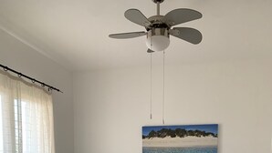 Un dormitorio con cama, mesita de noche, ventilador de techo y decoración de temática playera.