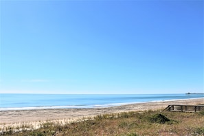 Uma praia com calçadão de madeira, areia e oceano.