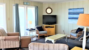 A living room with a television, two chairs, a sofa, a small table, and a lamp. - Oceanfront 4BR with Panoramic Views & Beach Access (Emerald Isle)
