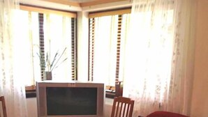 A living room with a TV, a red sofa, a wooden coffee table, and a vase. - Sólheimar (Husavik)