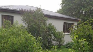 A building with a white exterior and dark roof, surrounded by dense greenery. - Sólheimar (Husavik)