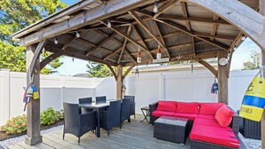 Una veranda coperta con un tavolo e sedie da pranzo, un divano rosso e un pavimento in legno.