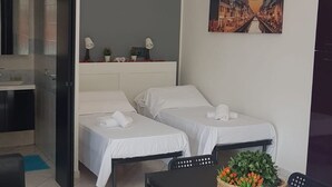 Een hotelkamer met twee bedden, een bureau met stoel, een kleine tafel met plant en een schilderij aan de muur.