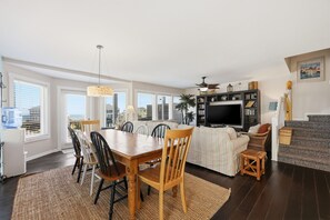 A spacious living area with a dining table, chairs, a sofa, a TV, and a bookshelf.