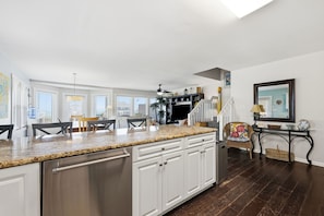 A spacious kitchen with a granite countertop, white cabinetry, and a built-in dishwasher. - Ocean View Second-Row Duplex | Spacious 5BR | Beach Access Across Street (Emerald Isle)
