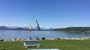 Une vue sur le lac, avec une zone herbeuse, un banc et des drapeaux.